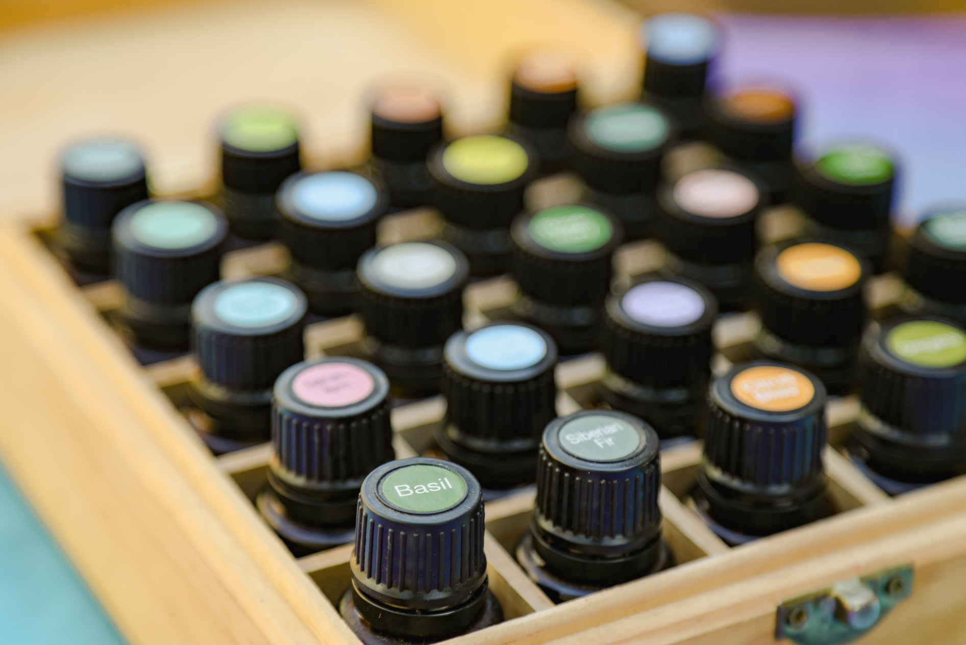 Top-down View of Essential Oil Bottles in Wooden Storage Box with Colorful Cap Stickers